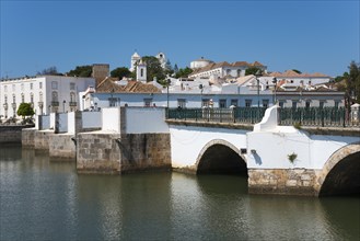 Brick bridge with arches over a river, picturesque cityscape with white buildings, Ponte Romana,