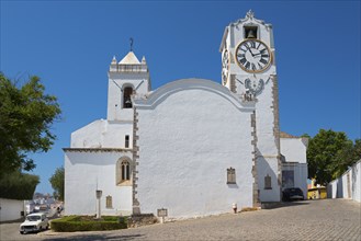 White church building with clock tower, surrounded by quiet cobbled streets, Igreja de Santa Maria