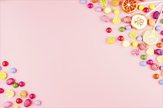 Flat lay view at sweet background of different type color and taste candies on pink. Space for text