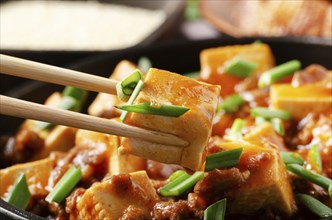 Mapo tofu dish of soybean curd piece being held in chopsticks