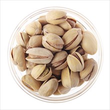 Pistachio nuts in glass bowl isolated on white background flat lay closeup view