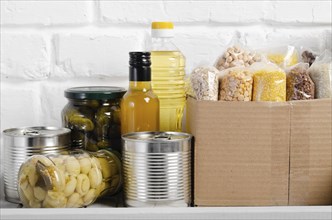 Set of uncooked foods on pantry shelf prepared for disaster emergency conditions on brick wall