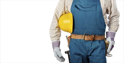 Middle aged contractor in overalls with tool belt holds yellow hard hat in his hands on white