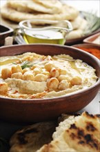 Low angle view at Hummus topped with chickpeas, olive oil and green coriander leaves on stone table