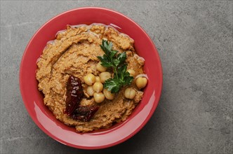 Flat lay view at hummus topped with chickpeas, sun dried tomatoes and green coriander leaves on