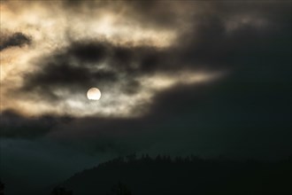 Sun above a mountain range breaking through morning clouds and fog, Leoben, Styria, Austria, Europe