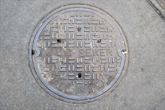 NYC manhole cover on a busy street in the New York City