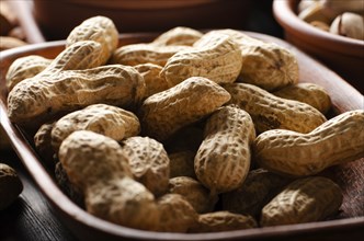 Peanuts in clay bowl on kitchen wooden table food background