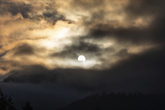 Sun above a mountain range breaking through morning clouds and fog, Leoben, Styria, Austria, Europe