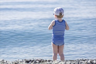 Little boy stay on the beach and look at the sea