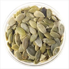 Peeled pumpkin seeds or pepitas in glass bowl isolated on white background flat lay closeup view