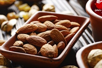 Almonds in clay bowl on kitchen wooden table food background