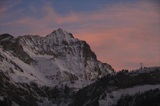 Sunlit pink clouds over Mount Arpelistock in winter