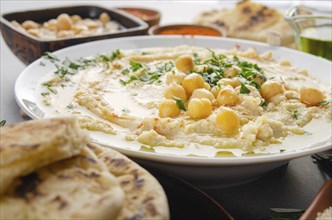 Closeup view at Hummus topped with beans olive oil and green coriander leaves on kitchen table with