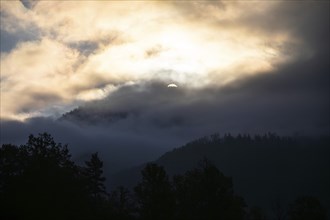 Sunrise, sun over a mountain range breaking through morning clouds and fog, Leoben, Styria,