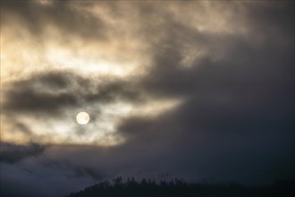 Sun above a mountain range breaking through morning clouds and fog, Leoben, Styria, Austria, Europe