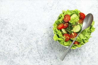 Healthy vegetables salad with fresh cucumbers, tomatoes, fresh iceberg salad leaves in a bowl on