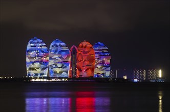 Scenic night view of buldings on Phoenix island with backlight and reflection in a sea in Sanya,