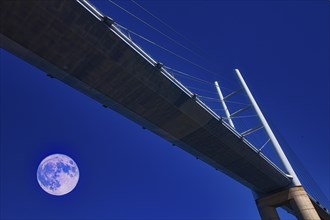 A modern bridge at night, illuminated by a clear sky with a full moon, Rügenbrücke, Stralsund,