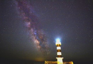 Lighthouse shining under a clear night sky of stars and the Milky Way, Colonia St. Jordi, Majorca,