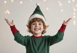 A cheerful boy dressed as a festive elf with green sweater and red details, with Christmas hat and