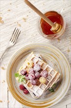 Flat lay view at Belgian waffles served with raspberries and mint leaf dusted with powdered sugar