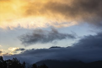 Clouds at dawn and wafts of mist over a mountain range, Berg Mugel, Leoben, Styria, Austria, Europe