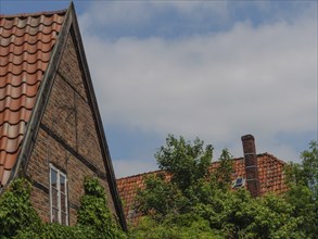 Detail of a half-timbered house with red tiled roofs and lush green trees, Steinfurt, North