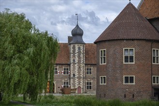 Historic castle with striking towers, red tiled roofs and a moat, surrounded by trees, Raesfeld,