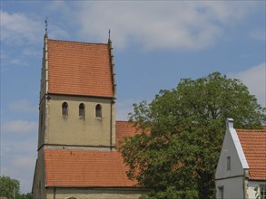 Church with striking tower and red tiled roofs under a blue sky, Steinfurt, North Rhine-Westphalia,