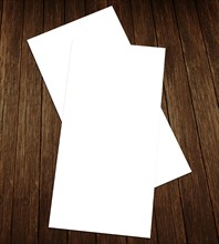 Two overlapping blank white sheets of paper on a dark wooden background, White blank flyer on