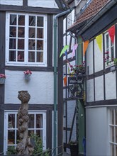 Half-timbered houses with colourful flags and flowers can be seen on a narrow pavement, Bremen,