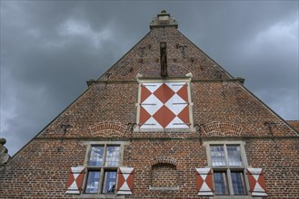 Close-up of a strikingly decorated gable of a historic brick building under a cloudy sky, Raesfeld,