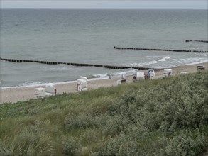 The beach features a row of beach chairs overlooking the sea, which is protected by wooden