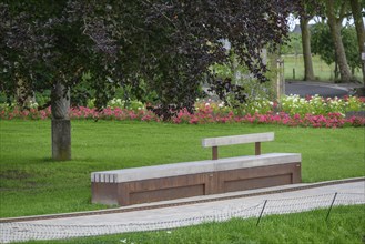 A quiet park with a bench under a tree, surrounded by green lawns and colourful flowers, Raesfeld,