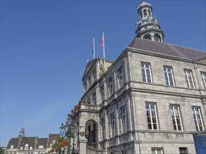 Elegant historic building with flags under a clear blue sky in a city, maastricht. netherlands