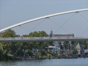 View of a modern bridge and historic buildings along a river in summer, maastricht. netherlands