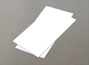 Three white sheets of paper laying on a gray surface, overlapping each other, White blank flyer on