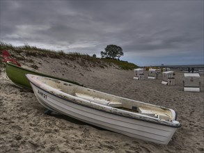 Lonely boats lie on the grey, cloudy beach under a gloomy sky, ahrenshoop, zingst, Baltic Sea,