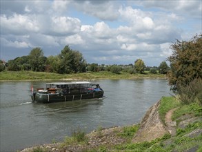 A boat sailing on a calm river on a cloudy day, zutphen, the netherlands