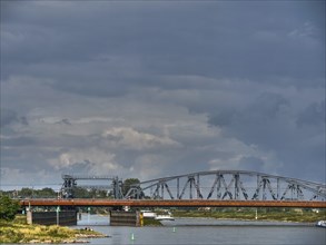 Metal bridge over a river under a cloudy sky in a quiet landscape, zutphen, the netherlands