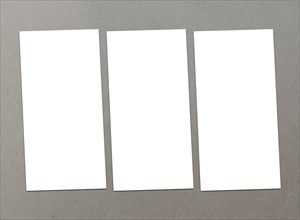 Three white sheets of paper arranged in a row on a gray surface, White blank flyer on background