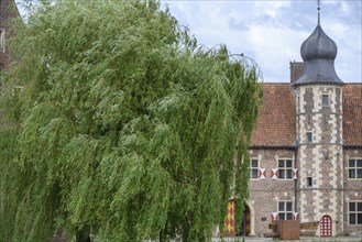 Partial view of a historic building with towers and tiled roofs, surrounded by trees, Raesfeld,