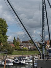 Small harbour with boats and historic buildings in the background, including a distant church tower