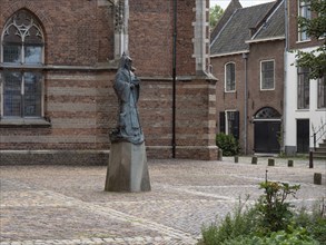 Statue in front of a historic building with Gothic architecture, surrounded by cobblestones,