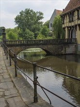 A historic stone bridge over a quiet river next to an old building, Steinfurt, North