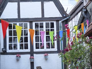 Colourful pennants and floral decorations on a half-timbered house in the old town, Bremen,