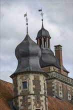 Close-up of a historic tower with decorative domes and weather vanes under a cloudy sky, Raesfeld,