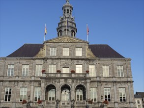 A historic building with a stone façade and several windows standing against the blue sky,