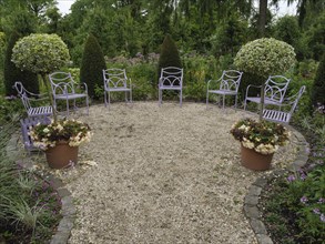 Round garden area with purple chairs and two potted plants, surrounded by green vegetation and